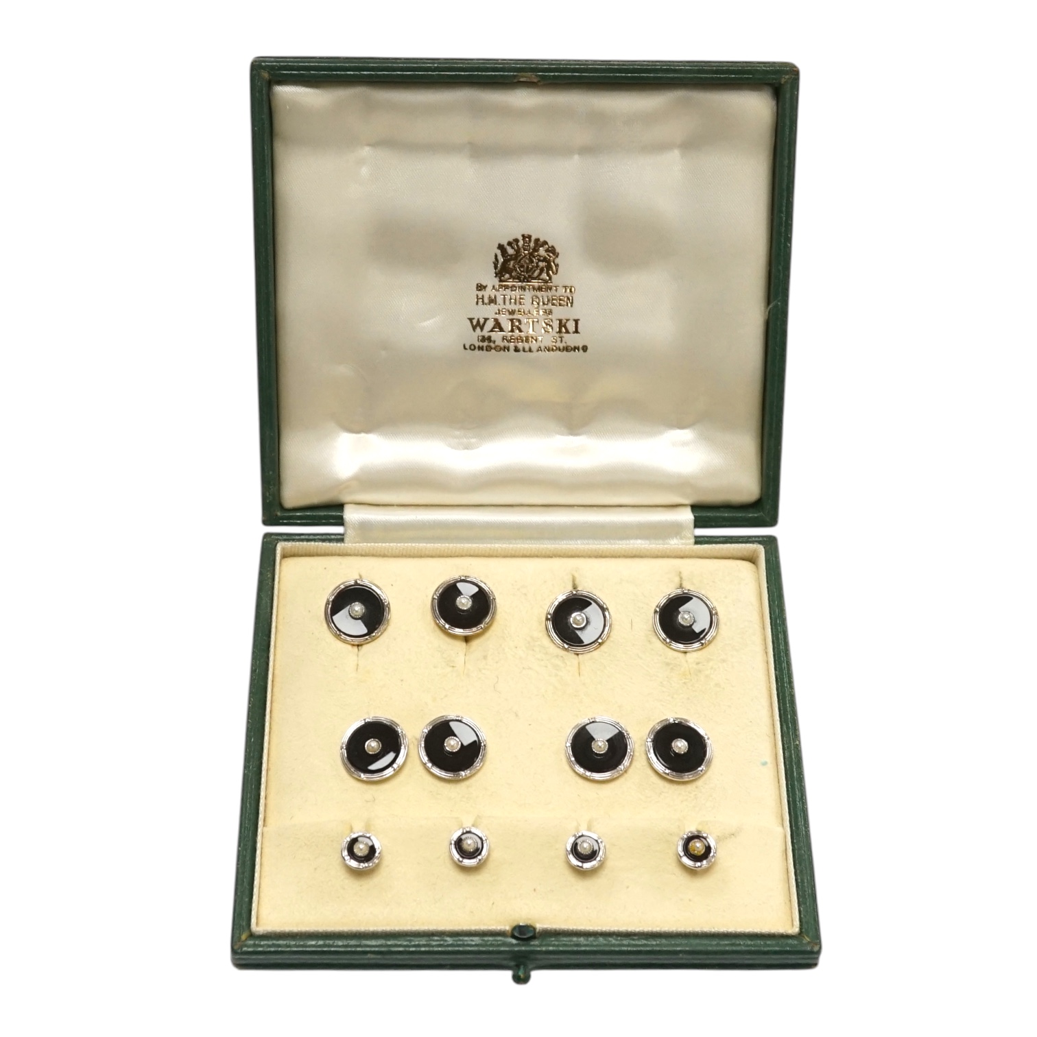 A 1960's 9ct white metal, black enamel and seed pearl set nine piece dress stud set by Cropp & Farr, housed in a Wartski fitted leather case. Condition - good